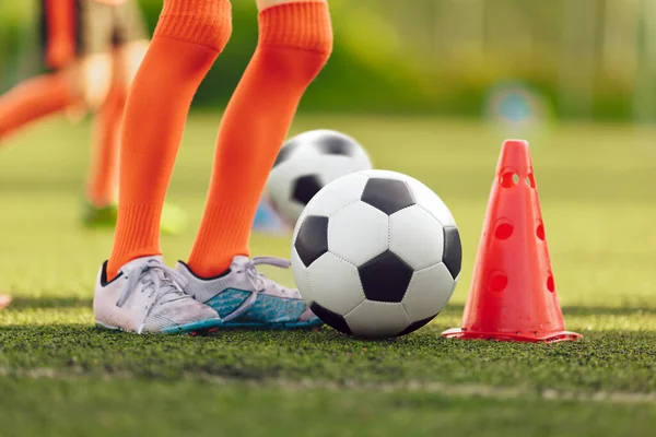 年轻足球运动员的腿在训练操练 儿童足球夏令营 儿童在草地球场训练期间踢足球 — 图库照片