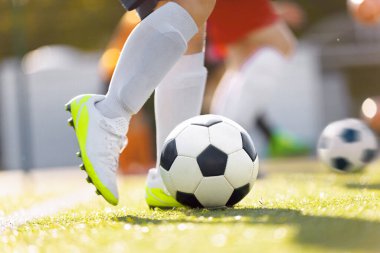 Çimen Sahada Futbol Topu Tekmeleyen. Futbol ekipmanları. Mükemmel Futbol Vuruşu. Futbol takımındaki genç futbolcu. Futbol ayakkabısı ve spor çorabı giyen bir öğrenci.