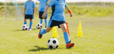 Genç Futbolcular Antrenmanda Topa Tekmeliyor. Eğitim Tatbikatında Koşan Çocuklar. Slalom Tatbikatında Çocuk Tekmeleme Balosu. Okul Futbolcuları Antrenman Oturumunda