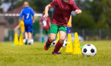 Blue and Red Soccer Team in Training Slalom Drill 'deki okul çocukları. Çocuklar çim tarlasında futbol oynuyor. Antrenman maçında Mutlu Okul Çocukları Balosu