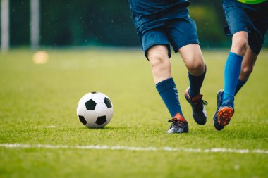 İki yetişkin futbolcu koşuyor ve futbol topunu tekmeliyor. Evet.