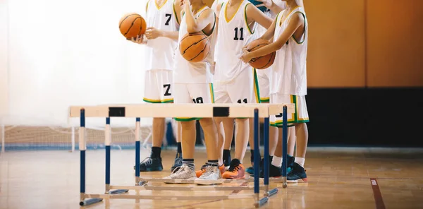 Young boys on basketball training. Group of school boys practicing basketball. Kids play sports during basketball training drills on a wooden court. Youth players ready to play training duel