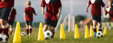 Profesyonel futbol koçluğu. Futbol antrenman konileri arasında top sürme tatbikatları. Genç Oyuncular Topları Tekmeliyor ve Topun Yeteneklerini Geliştiriyor. Okul Çocukları için Futbol Akademisi