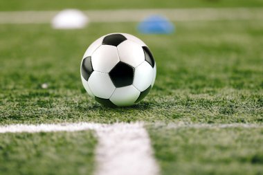 Antrenman sahasında klasik futbol topu. Futbol Suni Bölgesi. Bulanık Arkaplan 'daki futbol stadyumu. Genç Oyuncular Arka planda Egzersiz Yapıyor