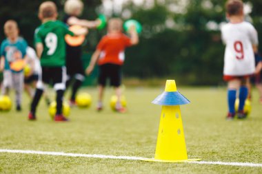 Anonim çocuklar güneşli bir yaz gününde koçlarıyla spor yaparlar. Çocukların futbol antrenman sahnesi. Çocuklar için futbol eğitimi. Çocuklar çimen antrenmanında futbol toplarını mutlulukla kovalıyorlar.