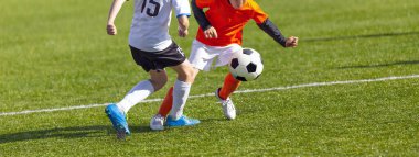 Çocuklar rekabetçi bir futbol maçı oynuyorlar. Genç Oyuncular Spor Düellosunda. Çocuklar Küçükler Ligi sırasında topa vuruyor.