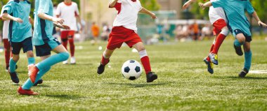 Futboldaki Genç Oyuncular. Çocuk, futbol topunu gol yolunda tekmeliyor. Okul çocukları futbol maçı oynuyorlardı. Çocuklar Küçükler Ligi sırasında topa vuruyor.