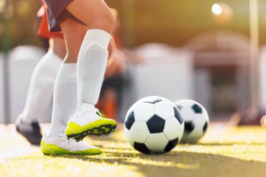 Güneşli bir günde futbolcu tekmeleme topu. Futbolcu çocuk Grass Pitch 'te beyaz kramponlarla koşuyor. Spor Futbolu Düşük Açı Arkaplanı