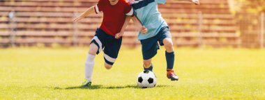 Çocuklar futbol maçı. Çocuklar Futbol Turnuvası Maçında Düello yapıyor. Topa vurma anı. Genç Tekmeleyen Top. Okul çocukları Çimen Sahasında Klasik Futbol Topu koşuyor