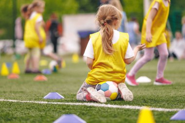 Futbol Eğitiminde Küçük Kız. Okul çocukları için futbol antrenmanı. Okul futbol sahasında bayan futbol antrenman takımı.