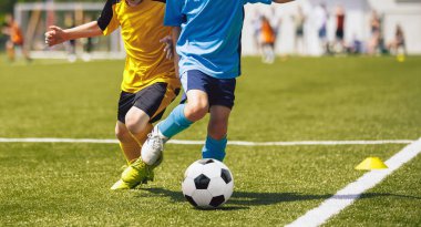 Erkekler futbol topunu tekmeliyor. Çocuklar çim tarlasında futbol oynarlar. Arka plandaki İzleyici Ebeveynler. Gençlik Oyuncuları çimen stadyumunda futbol maçını tekmeliyor. Gençler Futbol Turnuvası