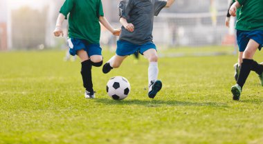 Çocuklar spor sahasında futbol oynuyorlar. Çocuklar Green Grass 'te futbol maçı yapıyor. Koşan Genç Futbolcular. Gençler Futbol Turnuvası Takım Yarışması