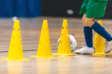 Çocuklar için futbol eğitimi. Spor salonunda futbol topuyla oynayan genç futbolcu. Spor arkaplanı.