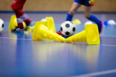 Spor salonunda futbol topuyla oynayan genç futbolcu. Çocuklar için futbol futsal eğitimi. Spor arkaplanı.