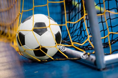 Gol Ağı 'nda Futsal Ball. Okul Spor Salonundaki Çocuklar İçin Kapalı Futbol Sınıfı. Futsal Zeminde Beyaz ve Siyah Futbol Topu. Okul öncesi çocuklar için spor futbol antrenmanı.