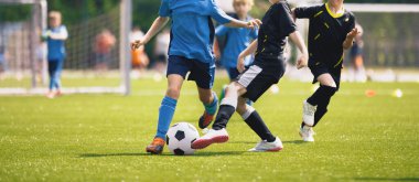 Mutlu çocuklar futbol maçında yarışıyor. Genç çocuklar futbol oynuyor. Çocuklar sporda eğleniyor. Koşan futbolcular. Koşan ve futbol oynayan oyuncular arasındaki rekabet. Futbol okulu.