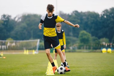Antrenman sahasında futbol topuyla koşan genç sporcu. Genç Futbol Kulübü antrenman oturumu. Futbol Antrenmanı Sportswea 'daki gençler. Spor Eğitimi Malzemeleri