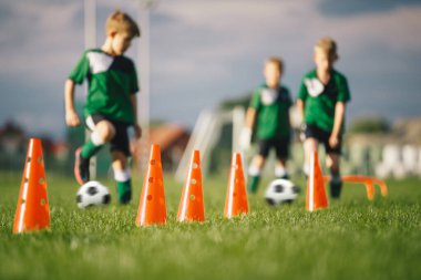 Çocuklar futbol antrenmanı yapıyor. Düelloda koşan ve futbol topunu tekmeleyen oyuncular arasında küçükler futbol antrenmanı yarışması. Futbol yaz kampında eğitim birimi.