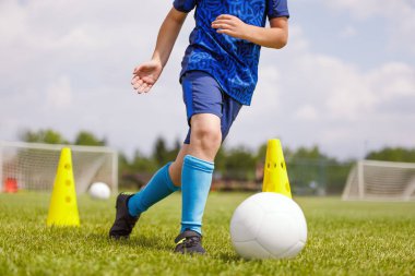 Okul sahasında futbol antrenmanına katılan bir çocuk. Beden eğitimi dersinde top süren genç futbolcu. Gençler için futbol antrenmanı