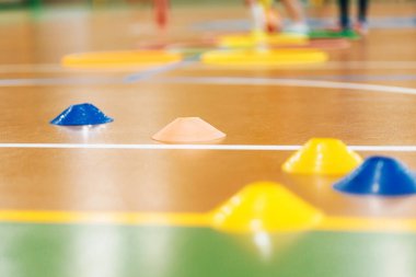 Çocuklar için kapalı spor eğitim konileri. Beden Eğitimi, Çeviklik Tatbikatları ve Eğlence Faaliyetleri için Spor Salonunda Renkli İşaretler