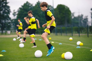 Çimen Sahasında Gençlik Futbol Eğitimi. Erkekler, koni ve toplarla futbol antrenmanı yapıyor. Futbol Akademisi Çalışma Oturumu