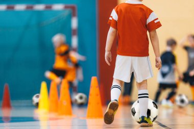 Çocuklar iç saha futbol antrenmanı. Genç Oyuncular Spor Salonunda Top Kontrolü ve Çeviklik Üzerinde Çalışıyor