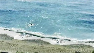 Resimli plaj, kumlu kıyıya vuran dalgalar. Deniz dalgaları kayalara çarpıyor. Kıbrıs Adası, Akdeniz.