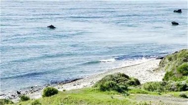 Resimli plaj, kumlu kıyıya vuran dalgalar. Deniz dalgaları kayalara çarpıyor. Kıbrıs Adası, Akdeniz.
