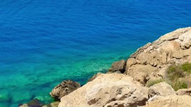 Resimli plaj, kumlu kıyıya vuran dalgalar. Deniz dalgaları kayalara çarpıyor. Kıbrıs Adası, Akdeniz.