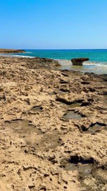 Resimli plaj, kumlu kıyıya vuran dalgalar. Deniz dalgaları kayalara çarpıyor. Kıbrıs Adası, Akdeniz.