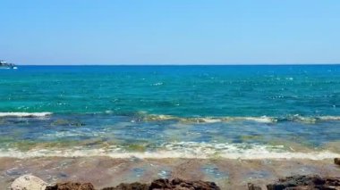 Resimli plaj, kumlu kıyıya vuran dalgalar. Deniz dalgaları kayalara çarpıyor. Kıbrıs Adası, Akdeniz.
