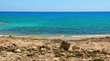 Resimli plaj, kumlu kıyıya vuran dalgalar. Deniz dalgaları kayalara çarpıyor. Kıbrıs Adası, Akdeniz.