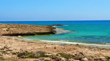 Resimli plaj, kumlu kıyıya vuran dalgalar. Deniz dalgaları kayalara çarpıyor. Kıbrıs Adası, Akdeniz.
