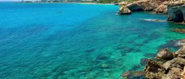 Resimli plaj, kumlu kıyıya vuran dalgalar. Deniz dalgaları kayalara çarpıyor. Kıbrıs Adası, Akdeniz.