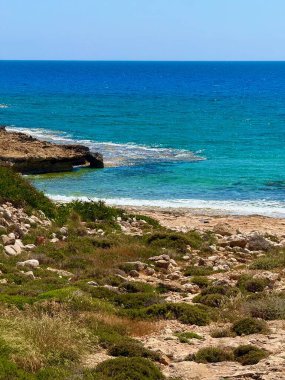 Resimli plaj, kumlu kıyıya vuran dalgalar. Deniz dalgaları kayalara çarpıyor. Kıbrıs Adası, Akdeniz.