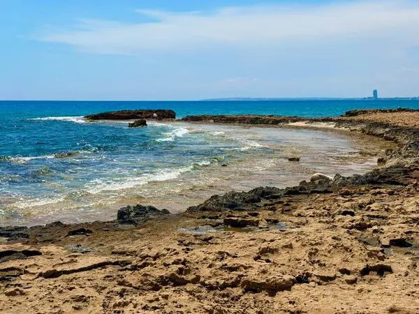 Resimli plaj, kumlu kıyıya vuran dalgalar. Deniz dalgaları kayalara çarpıyor. Kıbrıs Adası, Akdeniz.
