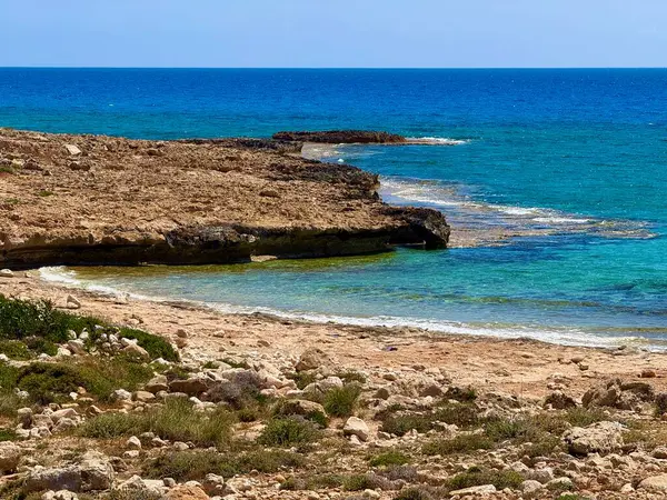 Resimli plaj, kumlu kıyıya vuran dalgalar. Deniz dalgaları kayalara çarpıyor. Kıbrıs Adası, Akdeniz.
