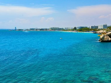 Resimli plaj, kumlu kıyıya vuran dalgalar. Deniz dalgaları kayalara çarpıyor. Kıbrıs Adası, Akdeniz.