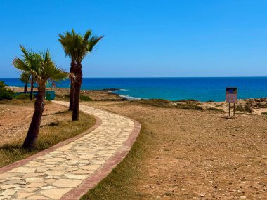 Resimli plaj, kumlu kıyıya vuran dalgalar. Deniz dalgaları kayalara çarpıyor. Kıbrıs Adası, Akdeniz.