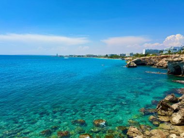 Resimli plaj, kumlu kıyıya vuran dalgalar. Deniz dalgaları kayalara çarpıyor. Kıbrıs Adası, Akdeniz.