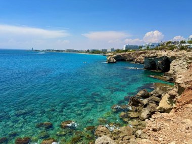 Resimli plaj, kumlu kıyıya vuran dalgalar. Deniz dalgaları kayalara çarpıyor. Kıbrıs Adası, Akdeniz.