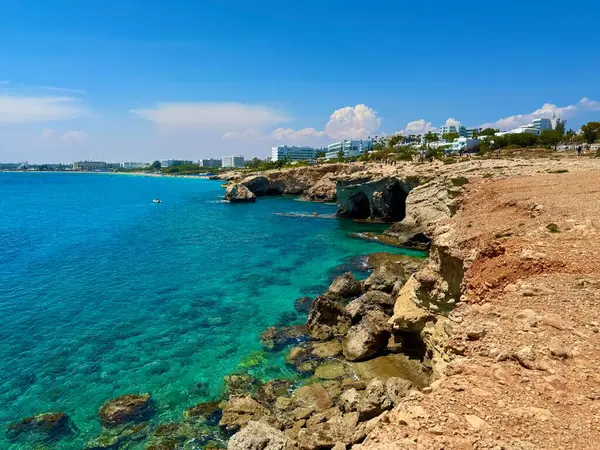 Resimli plaj, kumlu kıyıya vuran dalgalar. Deniz dalgaları kayalara çarpıyor. Kıbrıs Adası, Akdeniz.