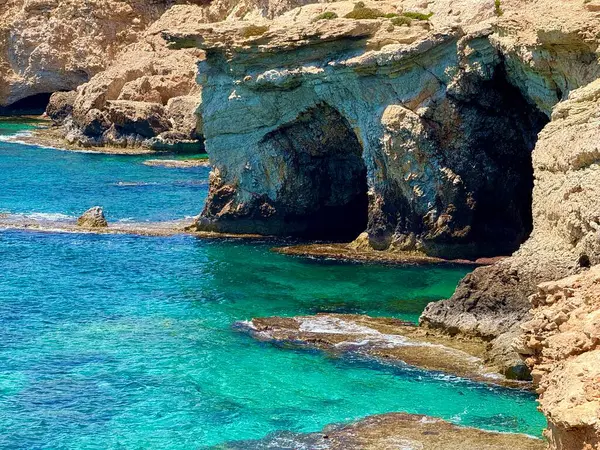 Resimli plaj, kumlu kıyıya vuran dalgalar. Deniz dalgaları kayalara çarpıyor. Kıbrıs Adası, Akdeniz.