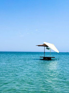 Resimli plaj, kumlu kıyıya vuran dalgalar. Deniz dalgaları kayalara çarpıyor. Kıbrıs adası, şemsiyeler, turist botları, Akdeniz.