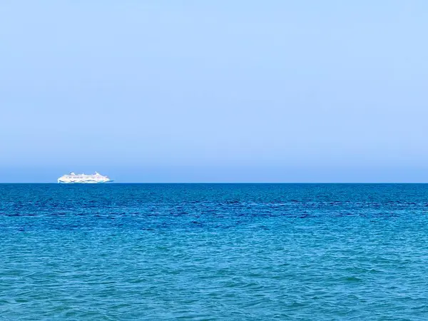 Resimli plaj, kumlu kıyıya vuran dalgalar. Deniz dalgaları kayalara çarpıyor. Kıbrıs adası, şemsiyeler, turist botları, Akdeniz.