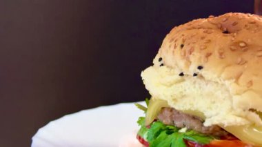 Beyaz tabakta domatesli ve yeşillikli büyük bir çizburger. Lezzetli, besleyici ve hazır yemek..