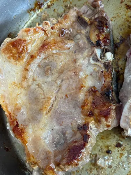 Closeup of a grilled pork chop. Pan-fried pork chops in frying pan.