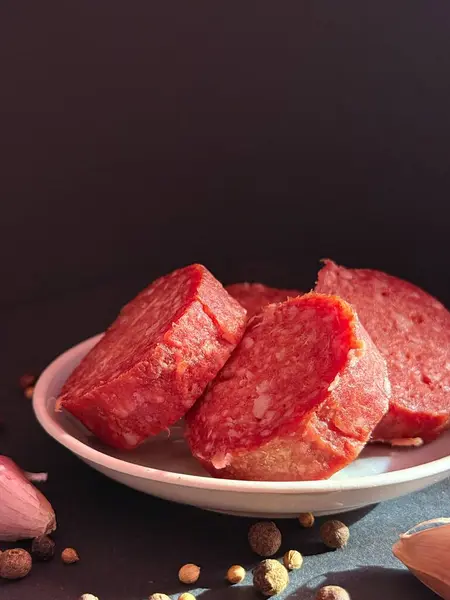 Slices of salami with garlic and pepper. Salami slices with shallots and peppercorns.