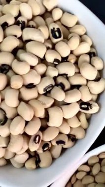 Beyaz fasulye, mercimek ve siyah bir yüzey üzerinde beyaz kâselerde siyah bezelyeler. Sağlıklı, sağlıklı, bitkisel gıdalar..