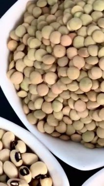 Beyaz fasulye, mercimek ve siyah bir yüzey üzerinde beyaz kâselerde siyah bezelyeler. Sağlıklı, sağlıklı, bitkisel gıdalar..
